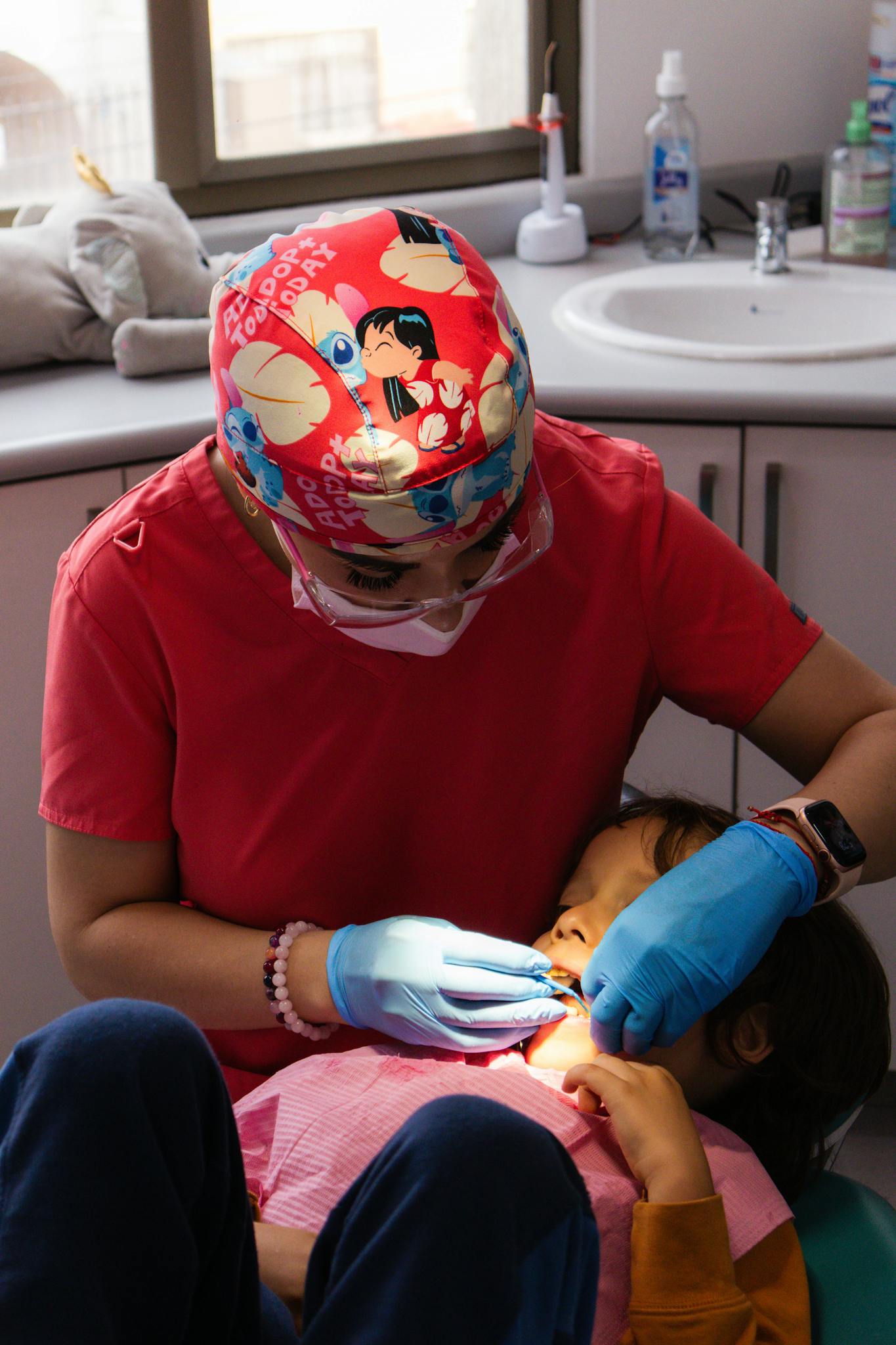 A pediatric dentist in a colorful cap examines a child in a dental clinic. Professional care.